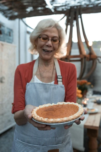 a woman holding a pie in a kitchen, a portrait, pexels contest winner, annie lebowitz, promotional image, pumpkin, al fresco