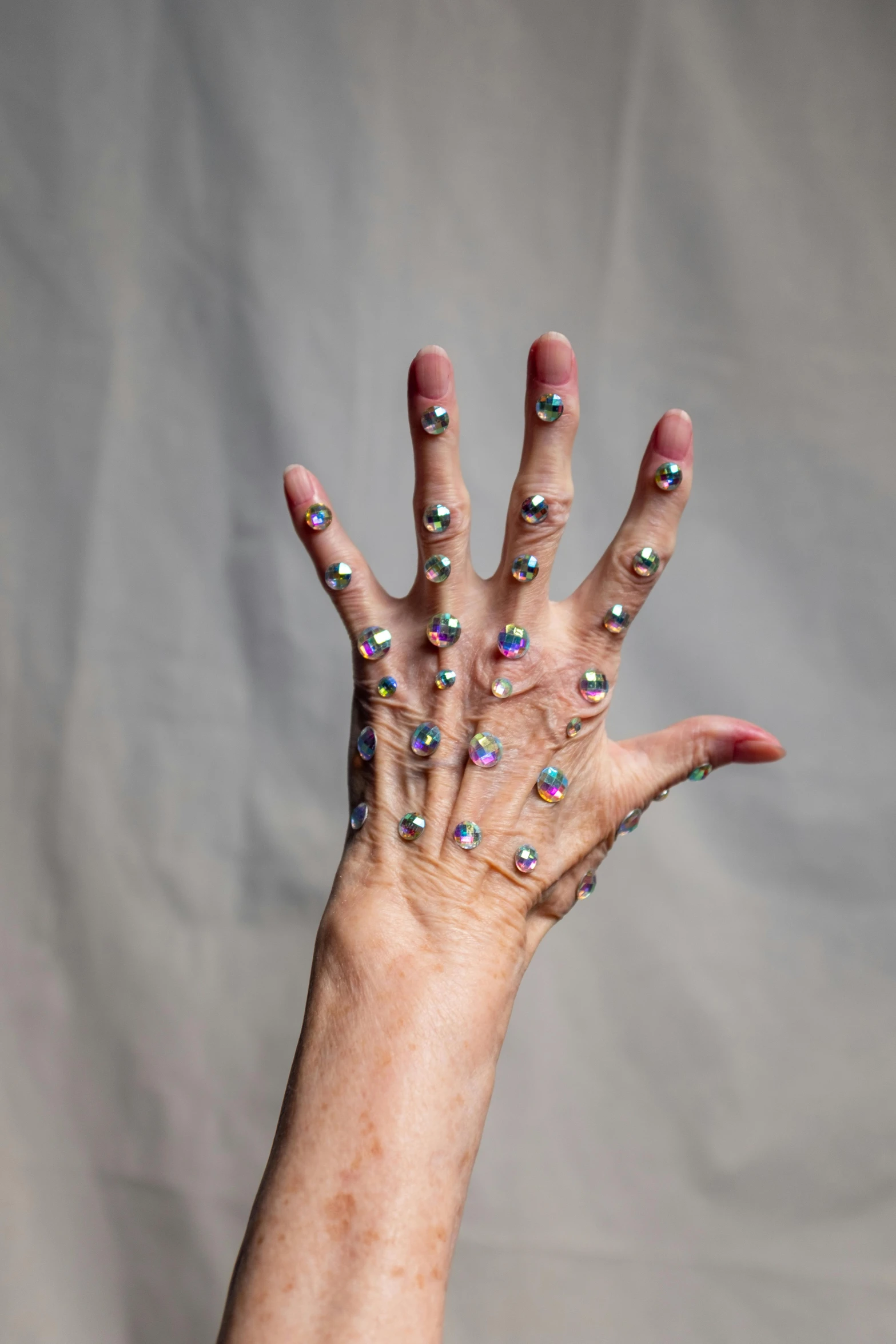 a close up of a person's hand with sprinkles on it, an album cover, by Maryam Hashemi, hyperrealism, covered in jewels, cybernetic limbs, photographed for reuters, body modification