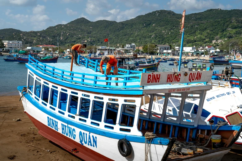 a blue and white boat sitting on top of a beach, by Sam Dillemans, pexels contest winner, vietnam, profile image, preparing to fight, maintenance photo