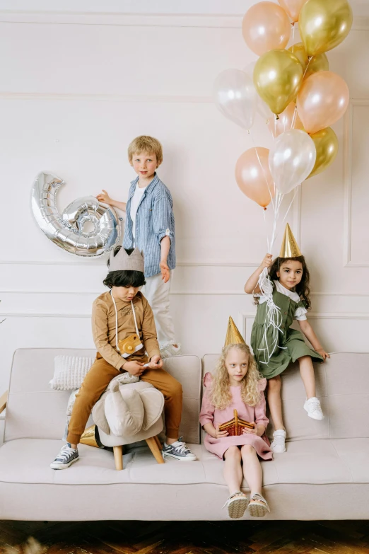 a group of children sitting on top of a couch, party balloons, beige fedora, promo image, collection product