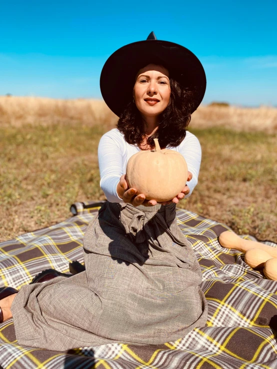 a woman sitting on a blanket holding a pumpkin, instagram, 15081959 21121991 01012000 4k, straw hat and overcoat, low quality photo, fortune teller