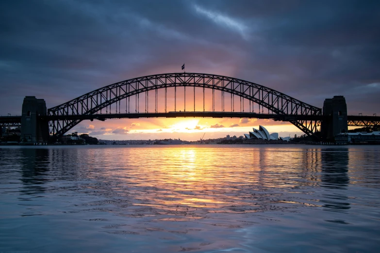 a bridge over a body of water under a cloudy sky, a picture, inspired by Sydney Carline, pexels contest winner, sunrise lighting, harbour, an ancient, former