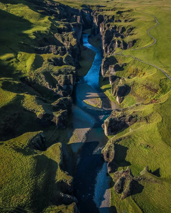 a river flowing through a lush green valley, by Harald Giersing, pexels contest winner, hurufiyya, chiseled formations, aerial, mid morning lighting, wall of water either side