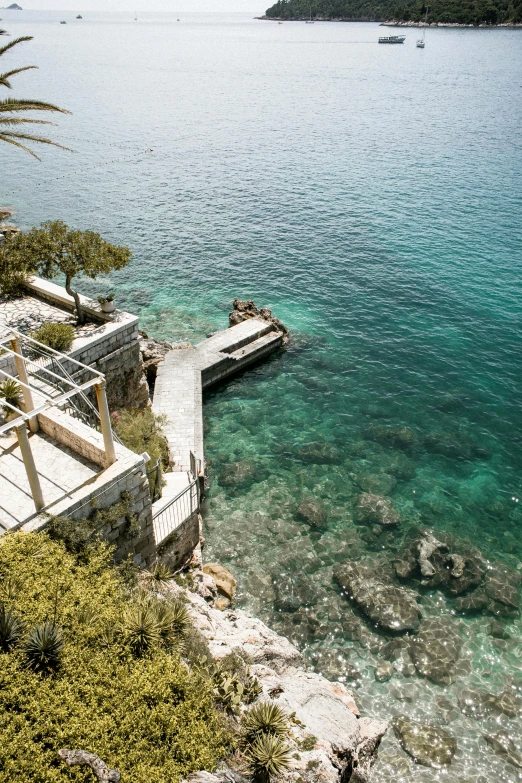 a dock in the middle of a body of water, croatian coastline, steps leading down, ocean cliff side, resort