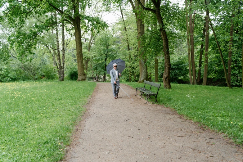 a man walking down a path with an umbrella, inspired by Béni Ferenczy, unsplash, realism, sitting on a park bench, alec soth : : love, berlin park, 2022 photograph