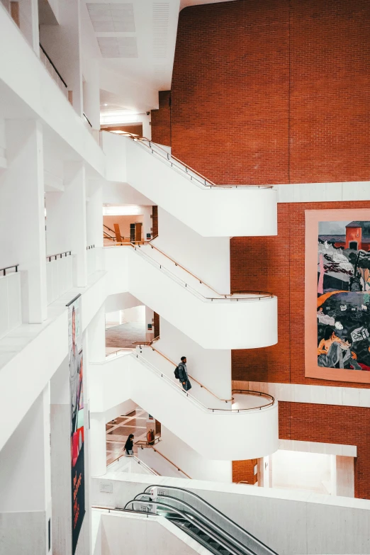 a staircase in a building with a painting on the wall, inspired by Bauhaus, pexels contest winner, modernism, shopping mall, pink marble building, white buildings, frank gehry architecture