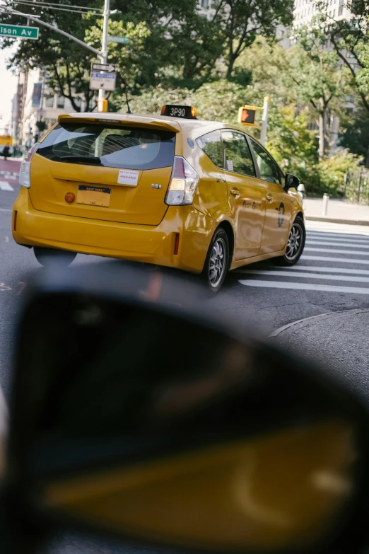 a yellow taxi cab driving down a city street, a picture, unsplash, square, pov from rear, shot on sony a 7 iii, ny