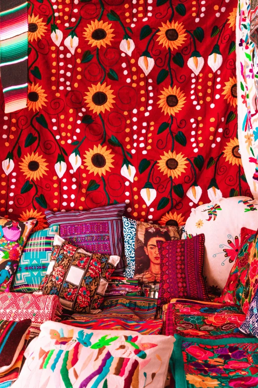 a room filled with lots of pillows and blankets, by Pacita Abad, maximalism, draped with red hybiscus, mexico, demur, quirky shops