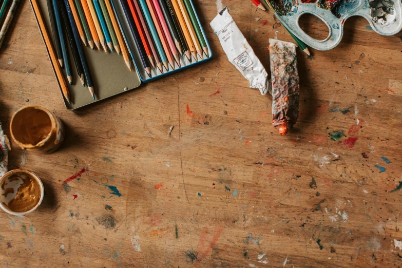 a wooden table topped with lots of art supplies, a child's drawing, trending on pexels, background image, broken composition, a high angle shot, featured art