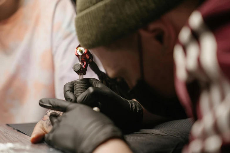 a man getting a tattoo on his arm, trending on pexels, hyperrealism, lachlan bailey, red ink sharp focus, black gold smoke ink, flat colour