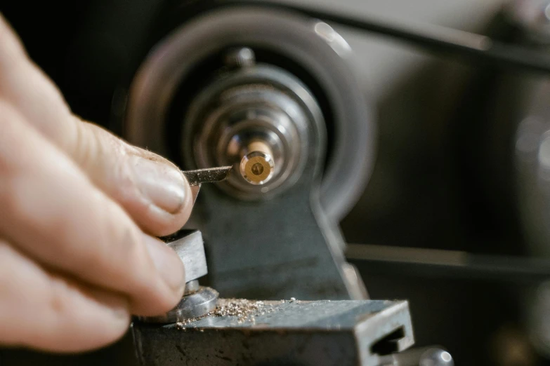 a close up of a person working on a machine, an engraving, trending on pexels, bead and reel, half turned around, tungsten, brown