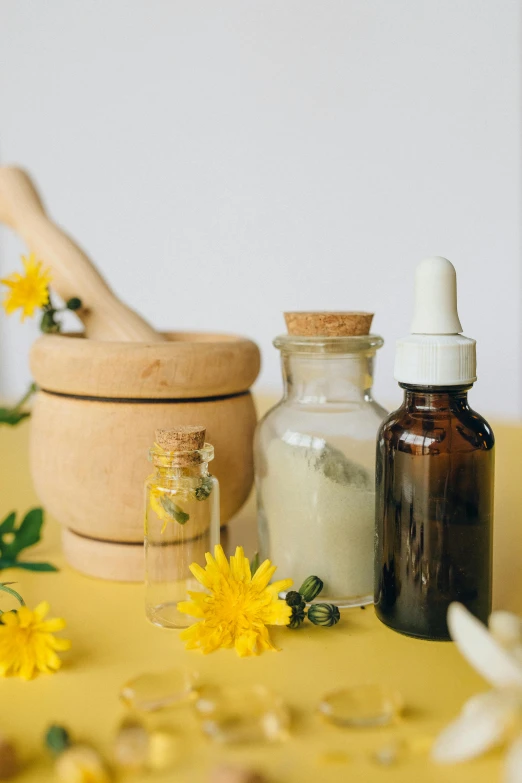 a yellow table topped with bottles and flowers, trending on pexels, renaissance, holistic medicine advertisement, cream, jars, a wooden