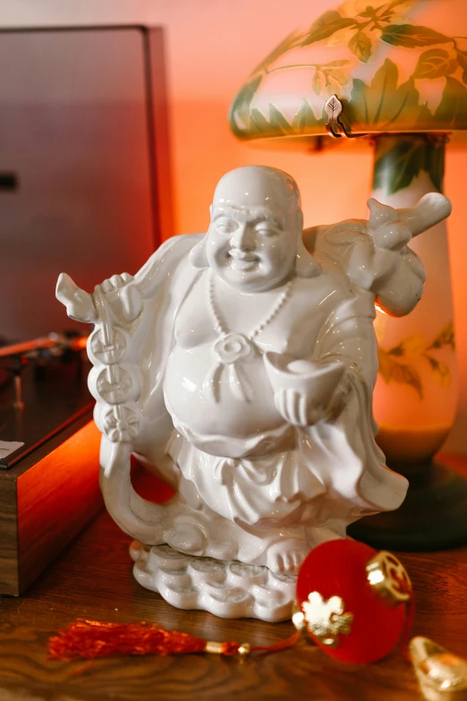 a buddha statue sitting on top of a table next to a lamp, a statue, giddy smirk, fine china, closeup of arms, from wheaton illinois