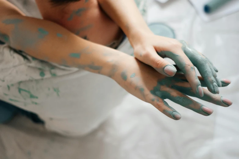 a woman sitting on top of a bed covered in green paint, inspired by Elsa Bleda, trending on pexels, action painting, holding each other hands, blue and grey, as well as the handyboy, delightful