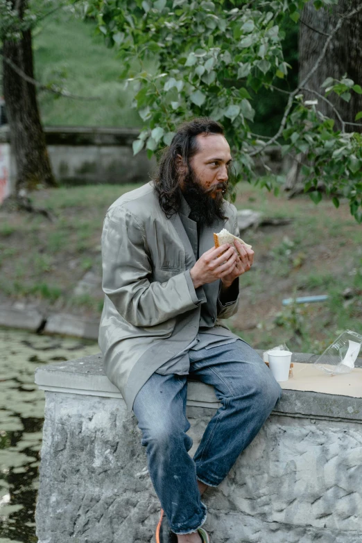 a man sitting on a wall eating a sandwich, by Attila Meszlenyi, pexels contest winner, hyperrealism, alejandro inarritu, rasputin as grubhub character, in a park, performance