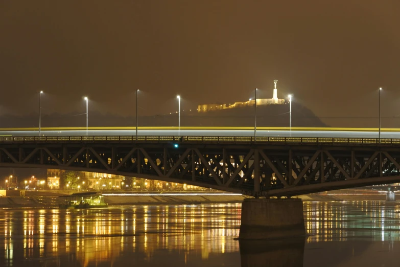 a bridge over a body of water at night, by László Balogh, pexels contest winner, yellow mist, austro - hungarian, panoramic, overpass