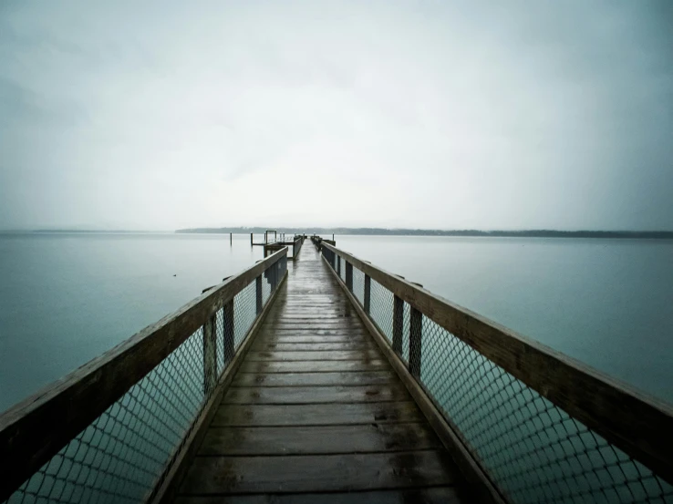 a pier in the middle of a body of water, by Matthias Stom, unsplash, hurufiyya, dreary, shot on sony a 7, looking out, detailed medium format photo