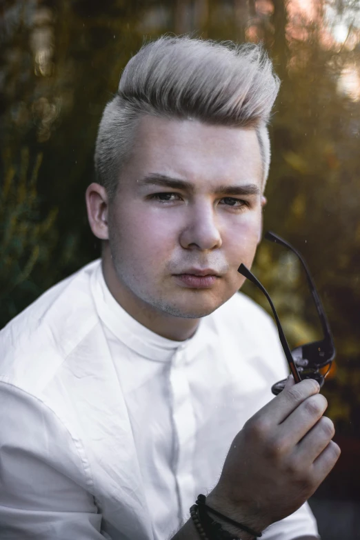 a man in a white shirt holding a pipe, inspired by Aleksander Gine, unsplash, photorealism, platinum hair, 18 years old, coloured photo, blonde and attractive features