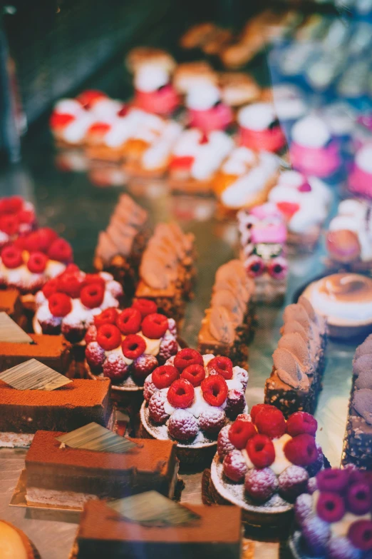 a display case filled with lots of different types of pastries, a tilt shift photo, by Daniel Gelon, trending on unsplash, art nouveau, square, brown and magenta color scheme, high angle close up shot, sea of parfait