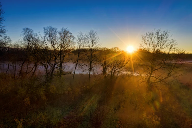 the sun is setting over a body of water, pexels contest winner, sun rays through trees, midwest countryside, bryan sola, today\'s featured photograph 4k