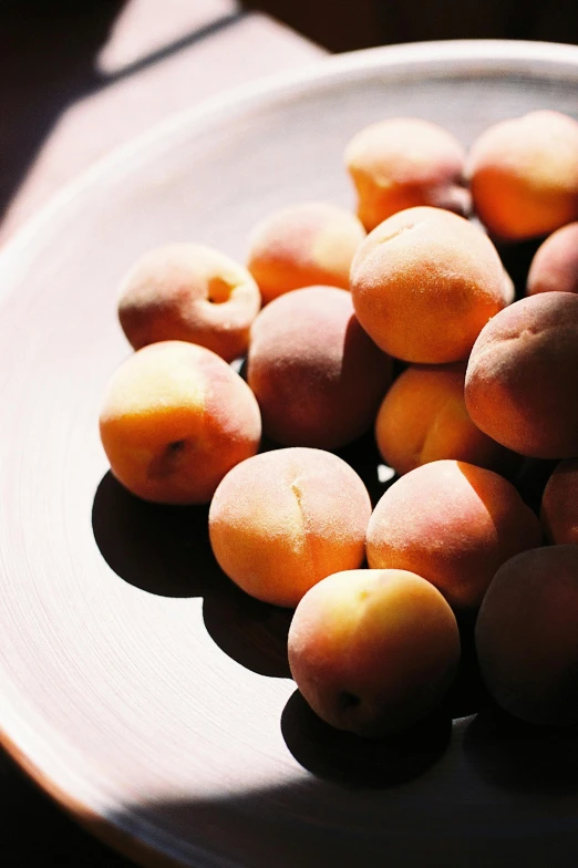 a plate of apricots sitting on a table, shades of gold display naturally, smooth matte, bashful, 2 1 0 mm