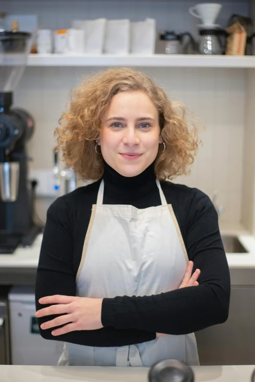 a woman standing behind a counter in a kitchen, a portrait, by Jacob Toorenvliet, professional profile picture, short curly blonde haired girl, sofya emelenko, square