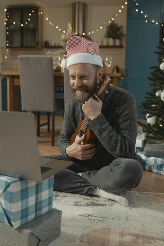 a man sitting on the floor using a laptop computer, inspired by Ernest William Christmas, reddit, violin, wearing a santa hat, promo image, digital still