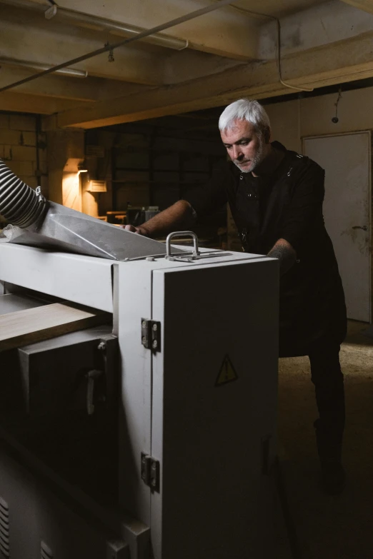 a man standing next to a machine in a room, unsplash, arbeitsrat für kunst, wood print, profile image, small manufacture, thumbnail