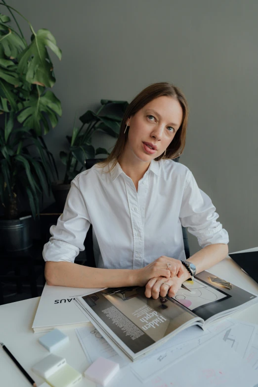 a woman in a white shirt sitting at a desk, inspired by Júlíana Sveinsdóttir, architect, influencer, catalogue photo, multiple stories