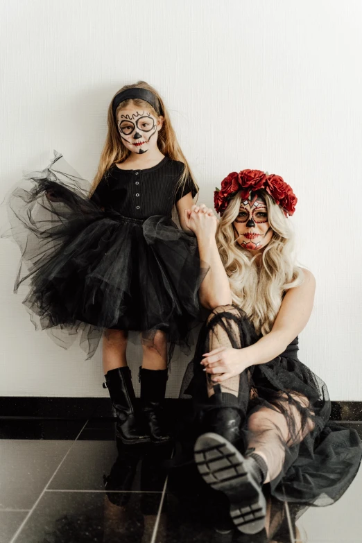 a couple of women sitting next to each other on a tiled floor, pexels contest winner, lowbrow, dia de los muertos makeup, daughter, wearing all black mempo mask, with a kid