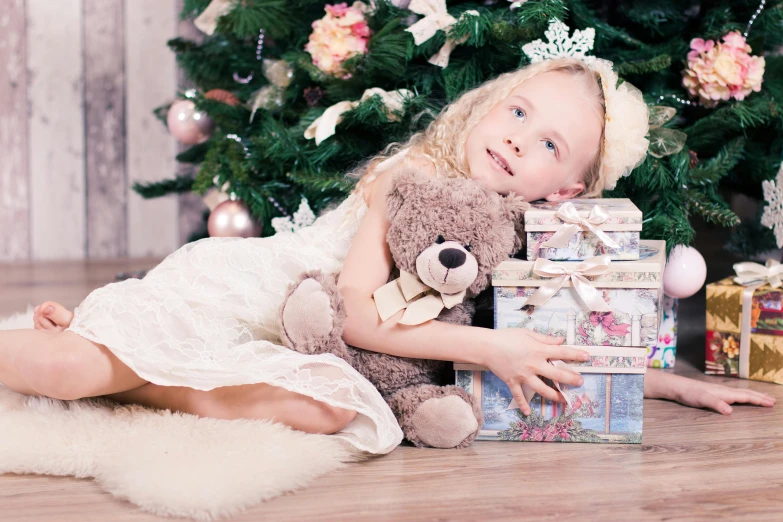 a little girl holding a teddy bear in front of a christmas tree, by Maksimilijan Vanka, pixabay, birthday wrapped presents, square, blonde - haired princess, softplay