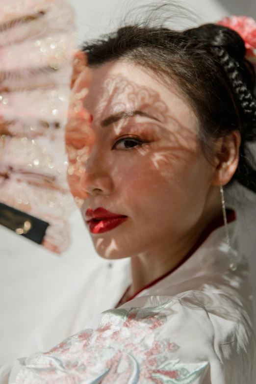 a woman holding a fan in front of her face, a picture, inspired by Xie Sun, trending on pexels, hyperrealism, faint red lips, white hanfu, portrait of modern darna, rectangle