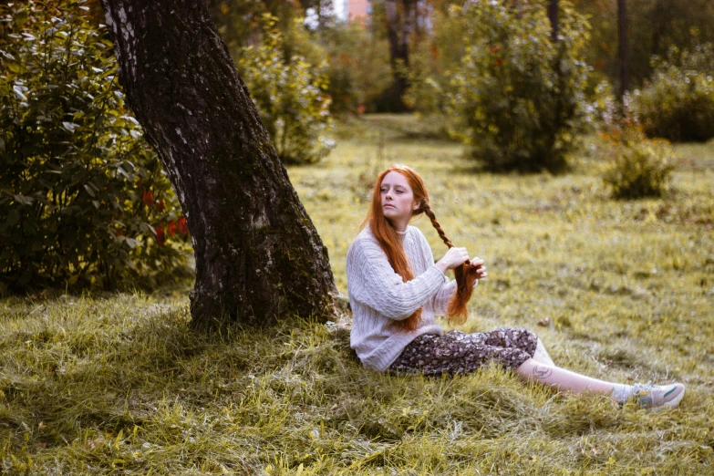 a woman sitting in the grass next to a tree, by Julia Pishtar, pexels contest winner, complex redhead braided hair, traditional russia, 15081959 21121991 01012000 4k, her hair is long and straight