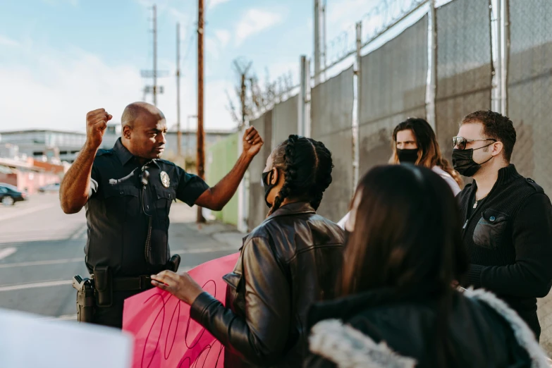 a group of people standing on the side of a road, trending on pexels, black arts movement, police officer, giving a speech, los angeles ca, portrait featured on unsplash