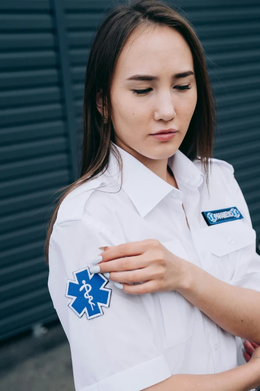 a woman in a white uniform is looking at her cell phone, a cartoon, trending on pexels, symbolism, shoulder patch design, ambulance, patch logo design, 🚿🗝📝