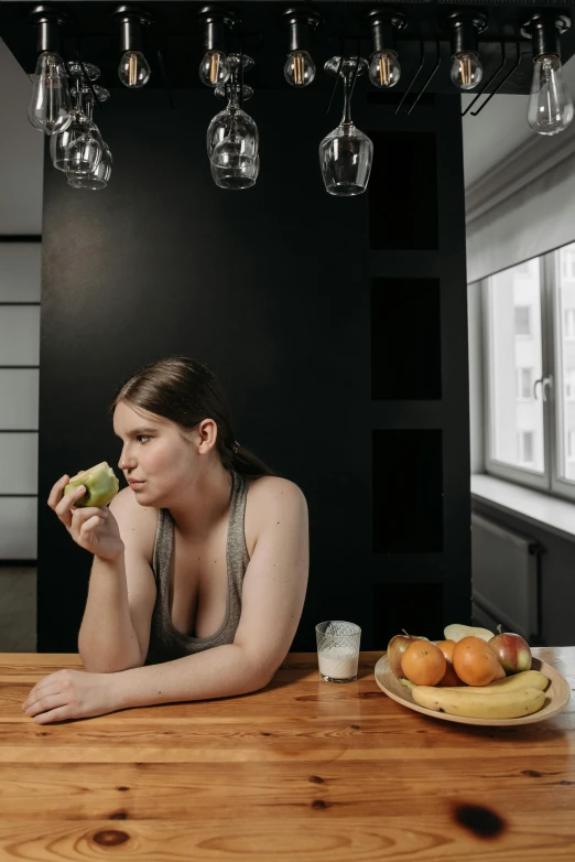 a woman sitting at a table eating an apple, inspired by Elsa Bleda, pexels contest winner, wearing a low cut tanktop, banana, obese ), contemplating