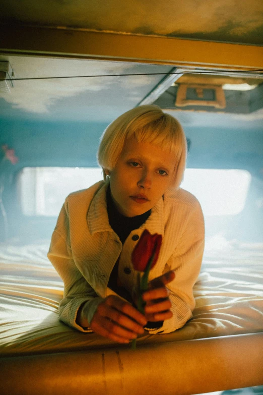 a woman sitting on top of a bed holding a rose, inspired by Nan Goldin, unsplash contest winner, magic realism, blonde boy with yellow eyes, movie still from blade runner, albino, in a spaceship