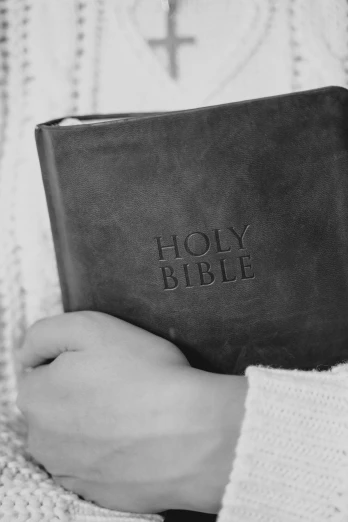 a person holding a bible in their hands, a black and white photo, by Robbie Trevino, children's, wearing leather, large)}], words