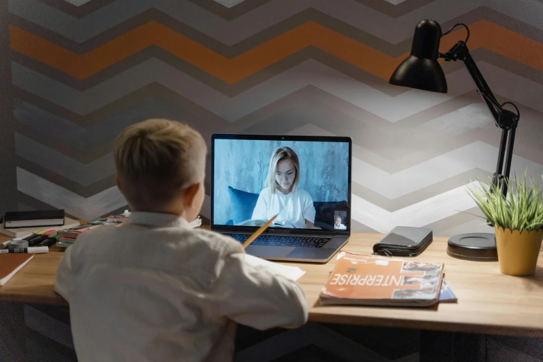 a young boy sitting at a desk in front of a laptop computer, by Julia Pishtar, pexels contest winner, video art, vertical orientation, kacper niepokolczycki, on a canva, lachlan bailey