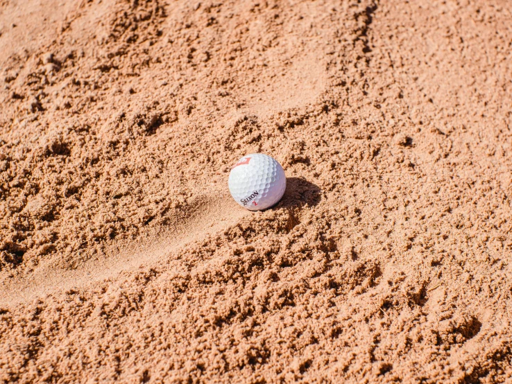 a golf ball sitting on top of a sandy beach, on ground