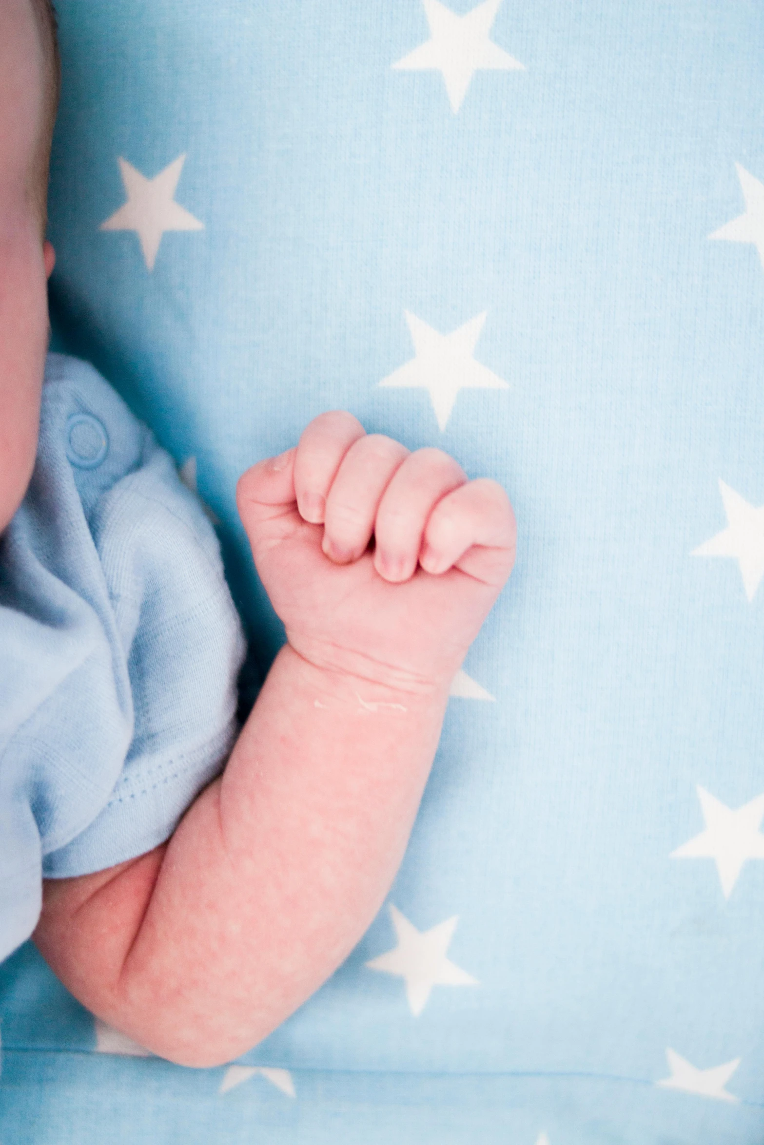 a baby laying on top of a blue blanket, by Ruth Simpson, shutterstock contest winner, symbolism, clenched fist, with stars, detail shot, high resolution photo