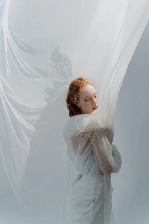 a woman in a white dress with a veil over her head, an album cover, inspired by Anna Füssli, a redheaded young woman, ignant, white gossamer wings, drapery