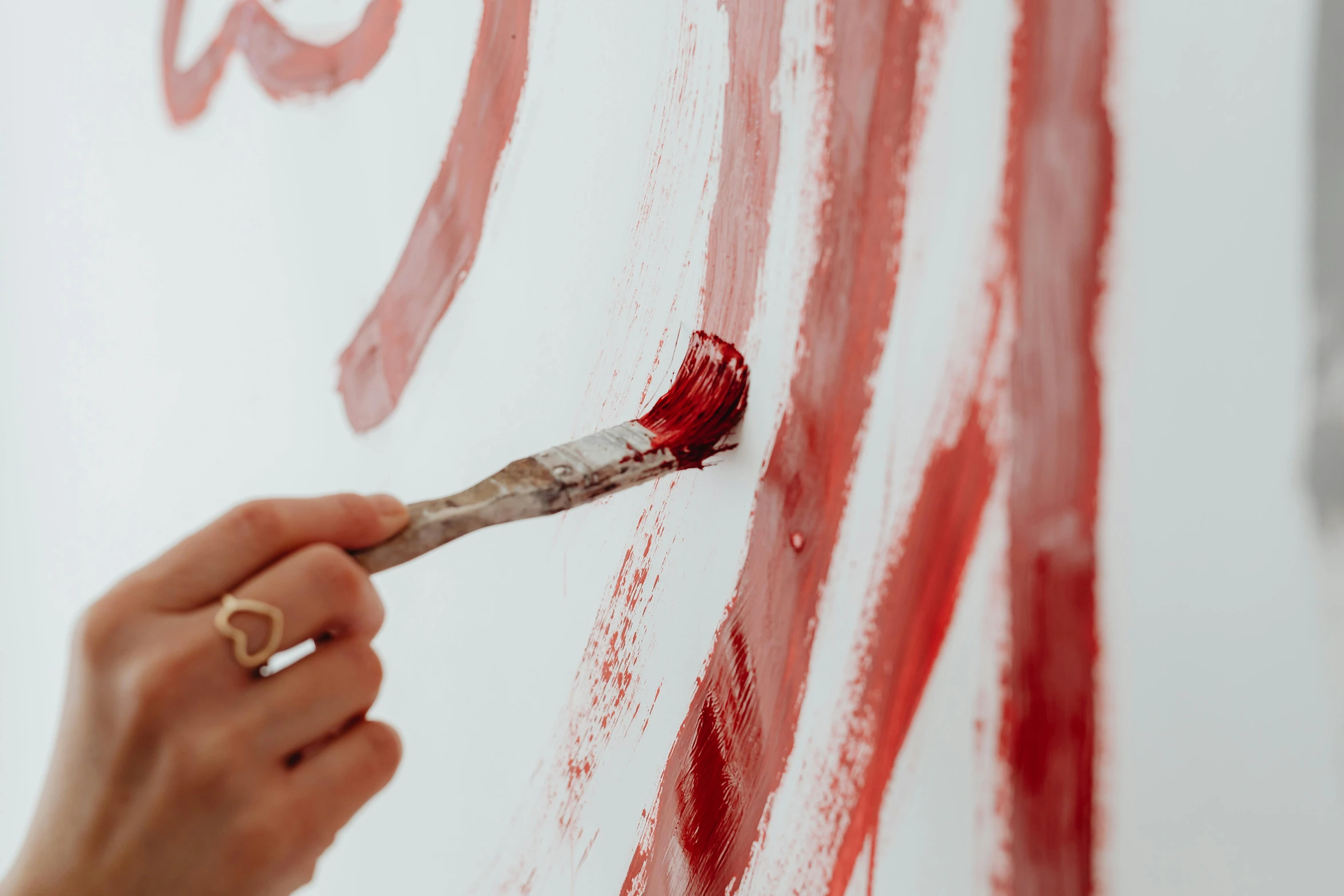 a person painting on a wall with a brush, inspired by Julian Schnabel, trending on pexels, cadmium red, on a canva, mid shot, red ink