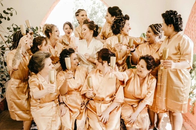 a group of women sitting next to each other, by Nicolette Macnamara, pexels contest winner, art nouveau, white robe with gold accents, cheers, in a gold suit, gif