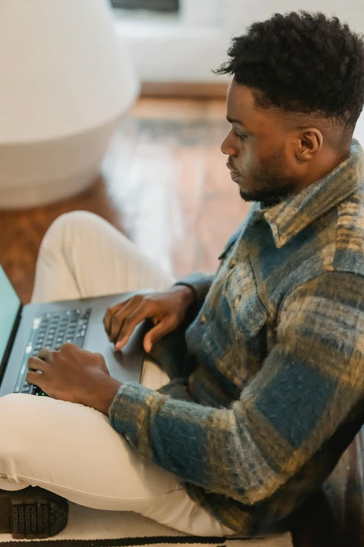 a man sitting on a chair using a laptop, trending on pexels, renaissance, ( ( dark skin ) ), brown, multicoloured, casually dressed