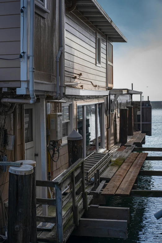 a boat sitting on top of a body of water, wood pier and houses, up close, in the evening, alleys