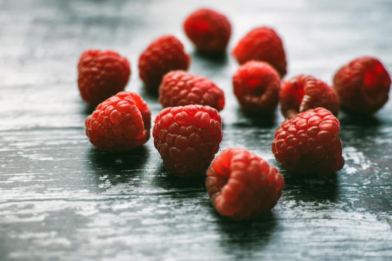 a bunch of raspberries sitting on top of a wooden table, pexels, grey, petite, in a row, brightly lit