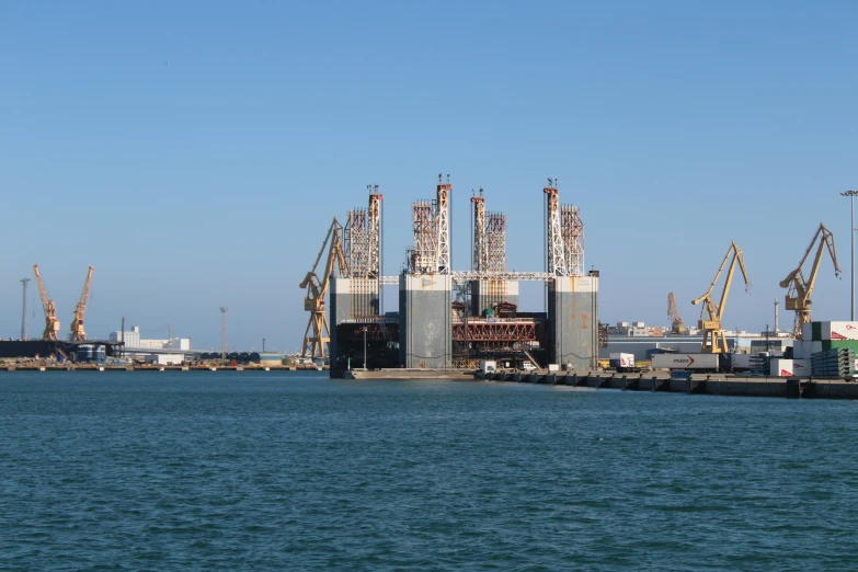 a large body of water with a bunch of cranes in the background, pexels contest winner, hurufiyya, mechanical superstructure, black sea, seen from outside, thumbnail