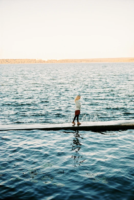 a man standing on a log in the middle of a body of water, boat dock, afternoon light, in water up to her shoulders, sydney hanson