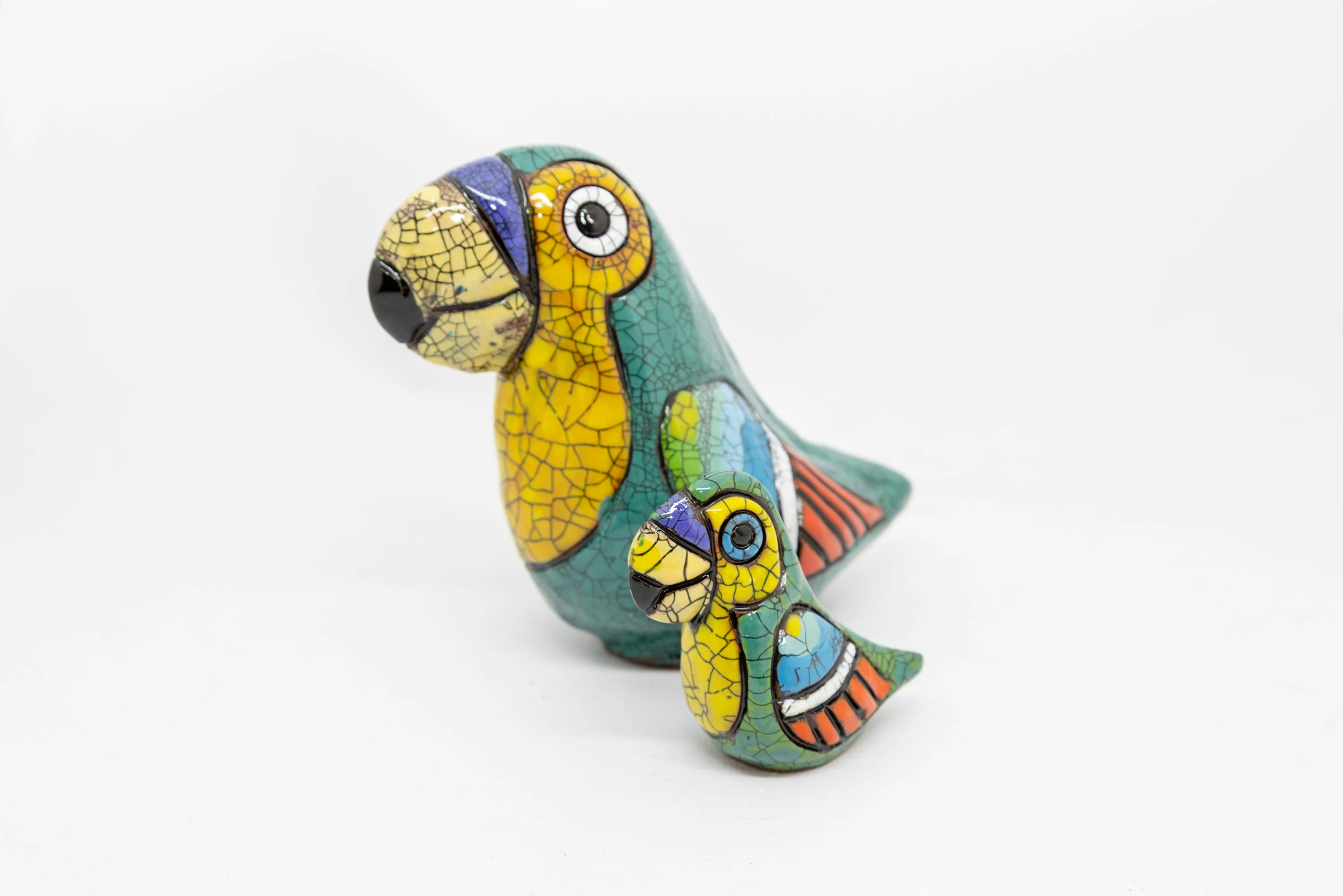 a colorful bird figurine sitting on top of a white surface, a portrait, inspired by Ignacio Bazan-Lazcano, cloisonnism, with chicks, with a big parrot, thumbnail, wooden